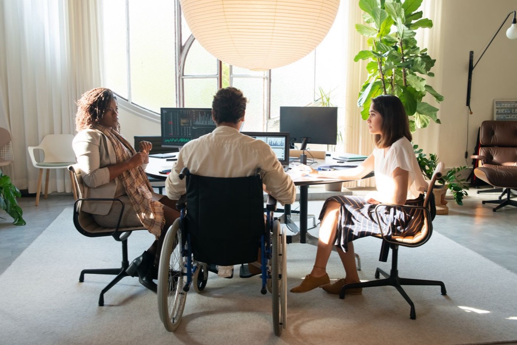Three colleagues in conversation in a bright office